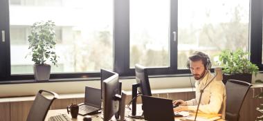 Man with headphones works at a computer workstation
